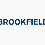 A slim, modern laptop placed on a wooden desk displaying the word "Brookfield" on its screen.