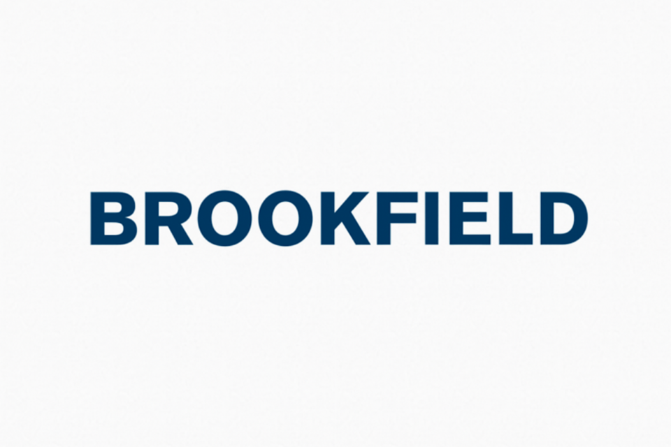 A slim, modern laptop placed on a wooden desk displaying the word "Brookfield" on its screen.